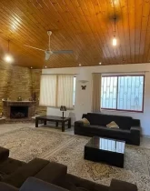 اتاق نشیمن با مبلمان قهوه ای و سقف چوبی ویلا 500 متری فلت در ایزدشهر 5864685458153
