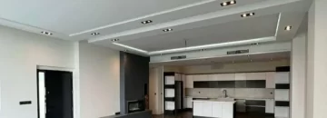 نورپردازی سقف سالن نشیمن و دیزاین سیاه سفید کابینت های آشپزخانه